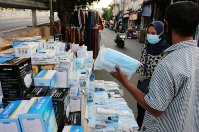 Pedagang masker melayani pembeli di kawasan Pasar Pagi Lama, Jakarta, Sabtu (17/7/2021).