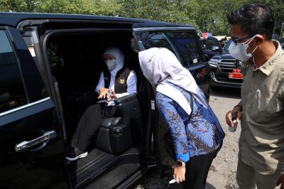 Ajudan menyemprotkan cairan disinfektan kepada Gubernur Jawa Timur Khofifah Indar Parawansa sebelum masuk ke mobil di Jawa Timur, Minggu (18/7/2021).