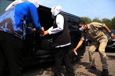 Ajudan menyemprotkan cairan disinfektan kepada Gubernur Jawa Timur Khofifah Indar Parawansa sebelum masuk ke mobil di Jawa Timur, Minggu (18/7/2021).