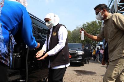 Ajudan menyemprotkan cairan disinfektan kepada Gubernur Jawa Timur Khofifah Indar Parawansa sebelum masuk ke mobil di Jawa Timur, Minggu (18/7/2021).
