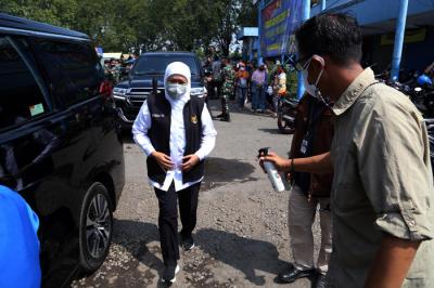 Ajudan menyemprotkan cairan disinfektan kepada Gubernur Jawa Timur Khofifah Indar Parawansa sebelum masuk ke mobil di Jawa Timur, Minggu (18/7/2021).