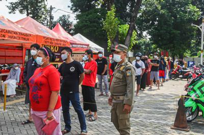 Petugas Satpol PP mengatur antrean warga yang ingin mencairkan Bantuan Langsung Tunai di Kecamatan Makasar, Jakarta Timur, Selasa (20/7/2021).
