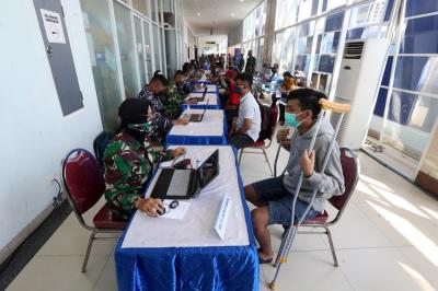 Peserta vaksin menutup muka ketika mendapat suntikan vaksin Covid-19 dalam serbuan vaksin masyarakat maritim di Gedung GSN, Jawa Timur, Senin (26/7/2021).