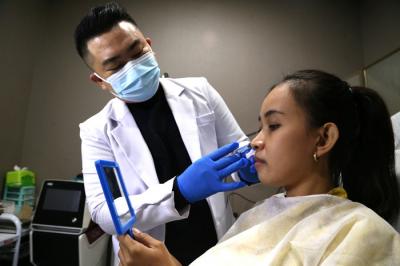 Dokter Michael Lawanto melakukan perawatan kulit wajah pasien di Beauty Skin dr MF Surabaya, Jawa Timur, Rabu (28/7/2021).