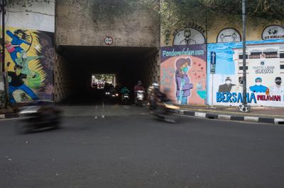 Pejalan kaki melintas di dekat tembok dengan mural melawan Covid-19 di kawasan Cikokol, Cawang, Jakarta, Rabu (28/7/2021).