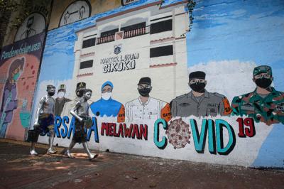 Pejalan kaki melintas di dekat tembok dengan mural melawan Covid-19 di kawasan Cikokol, Cawang, Jakarta, Rabu (28/7/2021).