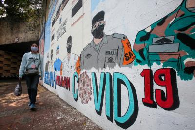 Pejalan kaki melintas di dekat tembok dengan mural melawan Covid-19 di kawasan Cikokol, Cawang, Jakarta, Rabu (28/7/2021).