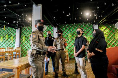 Petugas Satpol PP bersama TNI dan Polisi memberikan sosialisasi kepada pemilik rumah makan di kawasan Margonda, Depok, Jawa Barat, Rabu (28/7/2021).