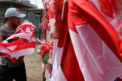 Penjual bendera merah putih dan pernak-pernik HUT Kemerdekaan Republik Indonesia yang Ke-76 merapikan dagangannya di Jalan Matraman, Jakarta (31/7/2021).