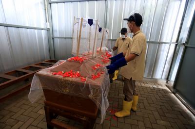 Petugas krematorium bersama keluarga duka mengangkat peti jenazah Covid-19 untuk dikremasi di TPU Tegal Alur, Jakarta, Sabtu (31/7/2021).