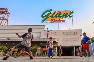 Anak-anak bermain bola di depan gedung gerai Giant yang resmi tutup, di kawasan, Tangerang, Banten, Senin (2/8/2021).