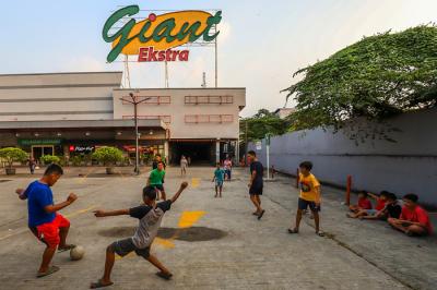 Anak-anak bermain bola di depan gedung gerai Giant yang resmi tutup, di kawasan, Tangerang, Banten, Senin (2/8/2021).