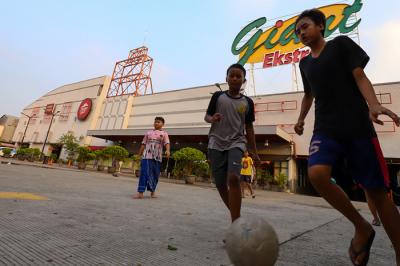 Anak-anak bermain bola di depan gedung gerai Giant yang resmi tutup, di kawasan, Tangerang, Banten, Senin (2/8/2021).