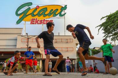 Anak-anak bermain bola di depan gedung gerai Giant yang resmi tutup, di kawasan, Tangerang, Banten, Senin (2/8/2021).