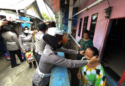 Petugas kepolisian Direktorat Lalulintas Polda Sulsel membagikan paket bantuan sembako pada warga pulau Lae Lae, Makassar, Jumat (6/8/2021).