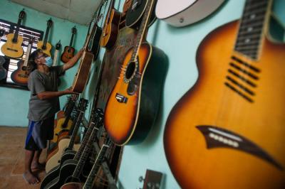 Pekerja menyelesaikan pembuatan gitar di sentra produksi dan reparasi gitar Pak Manto di Pejaten Timur, Pasar Minggu, Sabtu (7/8/2021).