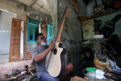 Pekerja menyelesaikan pembuatan gitar di sentra produksi dan reparasi gitar Pak Manto di Pejaten Timur, Pasar Minggu, Sabtu (7/8/2021).