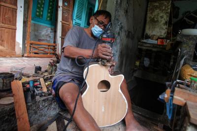 Pekerja menyelesaikan pembuatan gitar di sentra produksi dan reparasi gitar Pak Manto di Pejaten Timur, Pasar Minggu, Sabtu (7/8/2021).