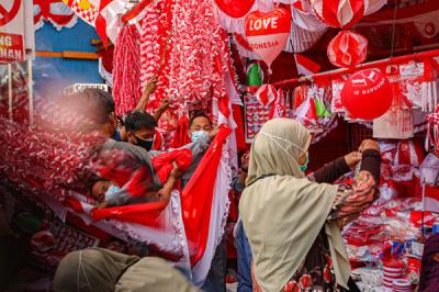 Pedagang melayani pembeli bendera merah putih di Pasar Jatinegara, Jakarta Timur, Senin (9/8/2021).