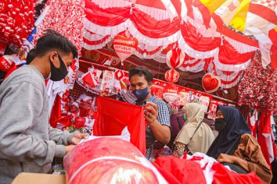 Pedagang melayani pembeli bendera merah putih di Pasar Jatinegara, Jakarta Timur, Senin (9/8/2021).