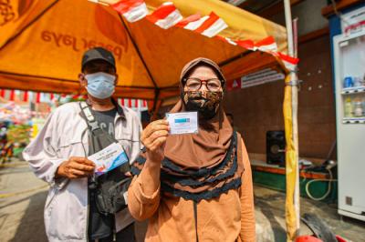 Pengunjung menunjukan sertifikat bukti telah melakukan vaksin kepada petugas sebelum masuk ke Gedung Pasar Jatinegara, Jakarta Timur, Senin (9/8/2021).