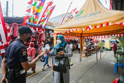 Pengunjung menunjukan sertifikat bukti telah melakukan vaksin kepada petugas sebelum masuk ke Gedung Pasar Jatinegara, Jakarta Timur, Senin (9/8/2021).