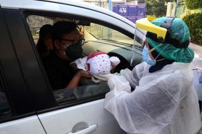 Dokter Spesialis Anak dr. Dini Adityarini memberikan vaksin pada anak ketika melayani vaksinasi secara drive thru di RS Kendangsari Merr, Selasa (10/8/2021).