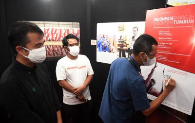 Pengunjung melihat foto yang dipamerkan dalam pameran foto jurnalistik Indonesia Tangguh Indonesia Tumbuh di Mal Central Park, Jakarta, Rabu (11/8/2021).