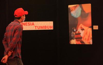 Pengunjung melihat foto yang dipamerkan dalam pameran foto jurnalistik Indonesia Tangguh Indonesia Tumbuh di Mal Central Park, Jakarta, Rabu (11/8/2021).