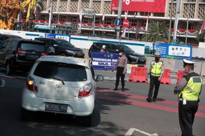 Petugas kepolisian melakukan pengaturan kendaraan saat pelaksanaan pengendalian mobilitas ganjil genap di Jalan MH Thamrin, Jakarta, Kamis (12/8/2021).