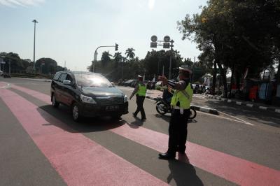 Petugas kepolisian melakukan pengaturan kendaraan saat pelaksanaan pengendalian mobilitas ganjil genap di Jalan MH Thamrin, Jakarta, Kamis (12/8/2021).