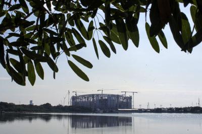 Warga melatih burung merpati dengan latar belakang proyek pembangunan Jakarta International Stadium di Tanjung Priok, Jakarta Utara, Kamis (12/8/2021).