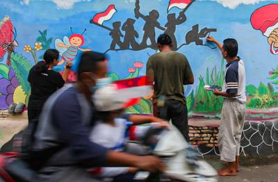 Winy bersama keluarganya saat membuat mural bertema keberagaman budaya Indonesia di Jalan Annur, Lubang Buaya, Jakarta Timur, Minggu (15/8/2021).