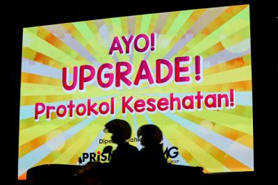 Kendaraan saat melintas dengan berlatar belakang himbauan upgrade protokol kesehatan agar rakyat Indonesia merdeka dari covid-19 di Jakarta, Senin (16/8/2021).