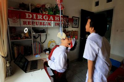 Pelajar SD saat mengikuti lomba makan kerupuk secara online dalam rangka memeriahkan HUT ke-76 RI di kawasan Graha Raya, Tangerang Selatan, Senin (16/8/2021).