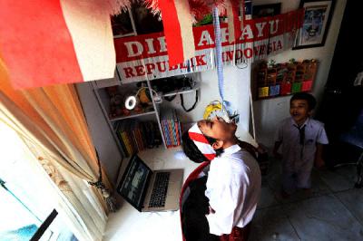 Pelajar SD saat mengikuti lomba makan kerupuk secara online dalam rangka memeriahkan HUT ke-76 RI di kawasan Graha Raya, Tangerang Selatan, Senin (16/8/2021).