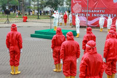Tenaga kesehatan mengibarkan bendera merah putih saat upacara peringatan kemerdekaan Ke-76 RI di RSDC-19, Wisma Atlet, Jakarta, Selasa (17/8/2021).