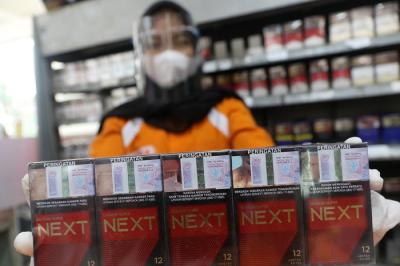 Pedagang menunjukkan bungkus rokok bercukai di Jakarta, Sabtu (21/8/2021).
