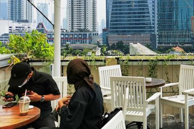 Pengunjung saat menikmati suasana di sebuah resto hotel dengan pemandangan gedung-gedung bertingkat di Jakarta Selatan, Minggu (22/8/2021).