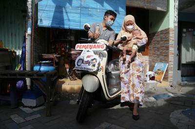 Sekti Bagus Saputro bersama istri dan bayinya berpose dengan satu unit sepeda motor Scoopy di Desa Kepuh Waru, Sidoarjo, Jawa Timur, Senin (23/8/2021).
