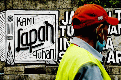 Warga saat melintas dengan berlatar belakang mural yang bertuliskan 'kami lapar tuhan' di Jakarta Pusat, Selasa (24/8/2021).