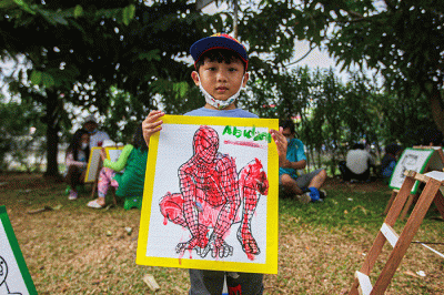 Seorang anak menunjukan hasil karya mewarnai miliknya di kawasan Banjir Kanal Timur, Jakarta, Minggu (29/8/2021).