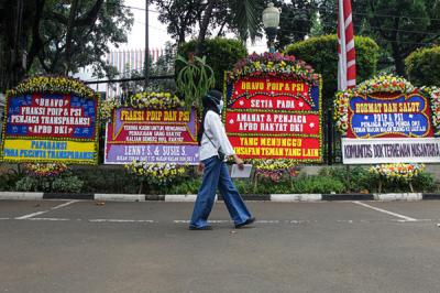Warga berjalan di dekat karangan bunga di area parkir Gedung DPRD DKI Jakarta, Kebon Sirih, Jakarta Pusat, Jumat (3/9/2021).