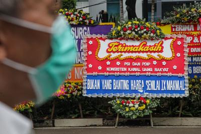 Warga berjalan di dekat karangan bunga di area parkir Gedung DPRD DKI Jakarta, Kebon Sirih, Jakarta Pusat, Jumat (3/9/2021).