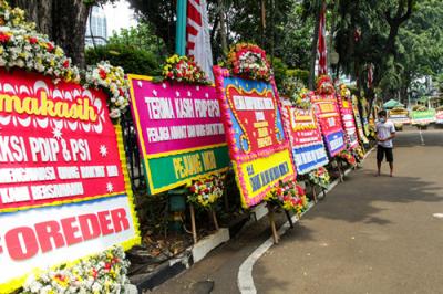 Warga berjalan di dekat karangan bunga di area parkir Gedung DPRD DKI Jakarta, Kebon Sirih, Jakarta Pusat, Jumat (3/9/2021).