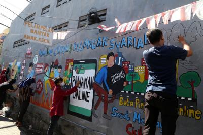 Mahasiswa Universitas Muhammadiyah Surabaya yang tergabung dalam Himpunan Mahasiswa Perbankan Syariah membuat mural edukasi di Surabaya, Senin (6/9/2021).