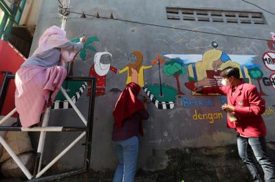 Mahasiswa Universitas Muhammadiyah Surabaya yang tergabung dalam Himpunan Mahasiswa Perbankan Syariah membuat mural edukasi di Surabaya, Senin (6/9/2021).