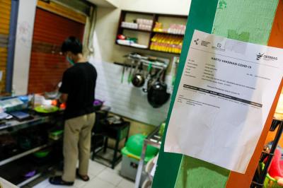 Pedagang menjaga toko sembakonya yang dipasang stiker sertifikat vaksin Covid-19 di Pasar Santa, Jakarta Selatan, Senin (6/9/2021).