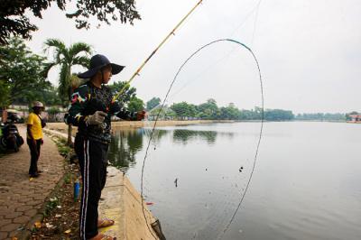 Warga saat memancing menggunakan alat pancing yang sudah dimodifikasi dengan jaring di Setu Pedongkelan, Depok, Jawa Barat, Minggu (12/9/2021).