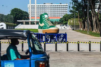 Warga melintasi dua tugu sepatu di Taman Lapangan Banteng, Jakarta Pusat, Jumat (17/9/2021).